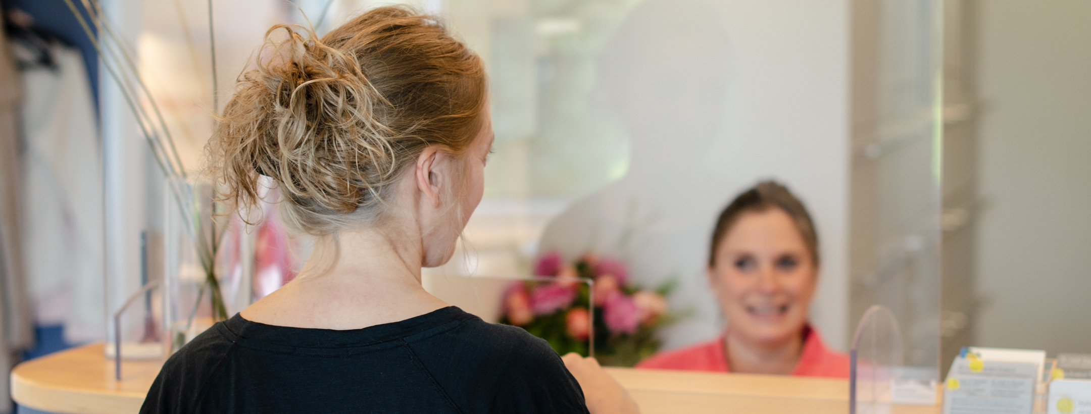 Patient:in am Tresen stehend von hinten aufgenommen