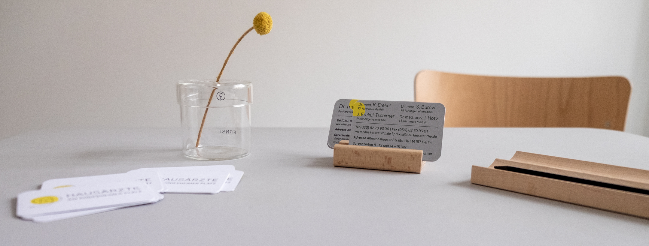 Vase mit einer gelben Blume und Visitenkarten der Ärzte.