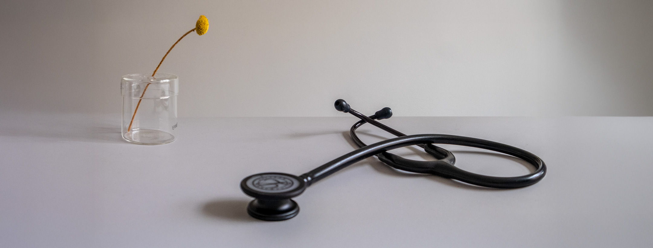 Foto eines Stethoskops neben einer Blume in einer transparenten Vase